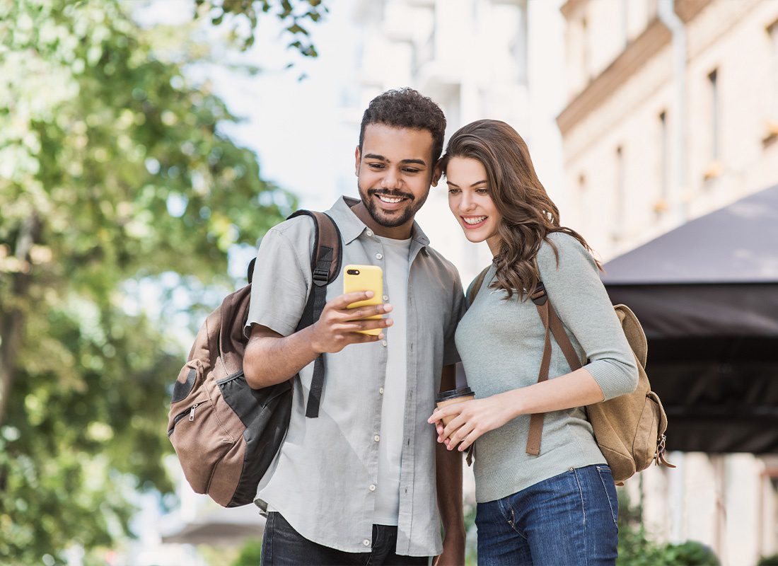 Read Our Reviews - Young Couple Using a Smartphone Outdoors on a Nice Sunny Day